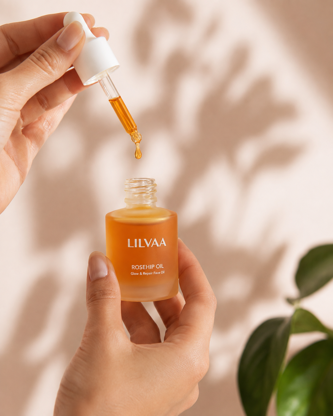A hand holding the LILVAA rosehip oil bottle while the dropper releases a single drop
